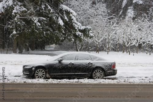 Iced and covered with a thick layer of snow car parked on the side of the road in a snowstorm