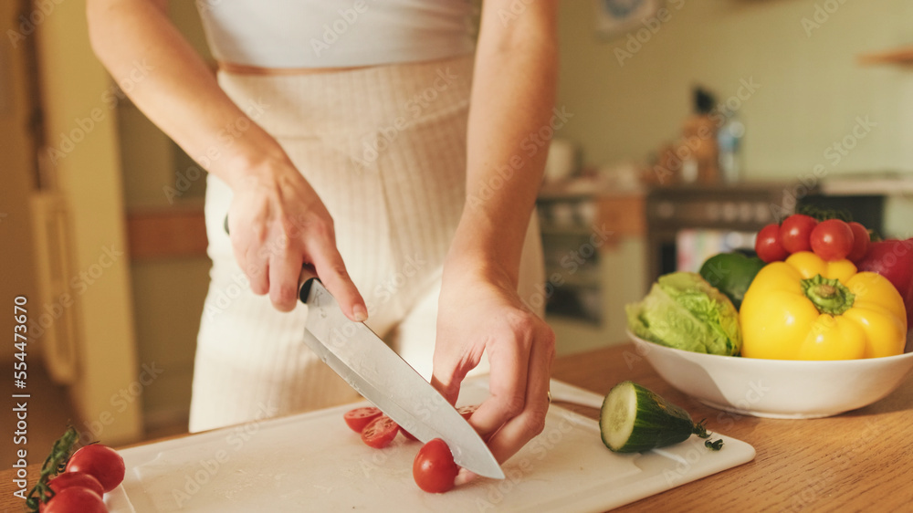 Close-up of young woman's hands cutting tomatoes making salad at home in the kitchen Close-up of young woman's hands cutting tomatoes making salad at home in the kitchen