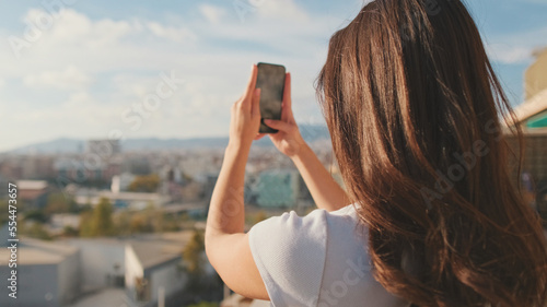 Close up, young woman takes photo on mobile phone while standing on the balcony at home. © Andrii Nekrasov