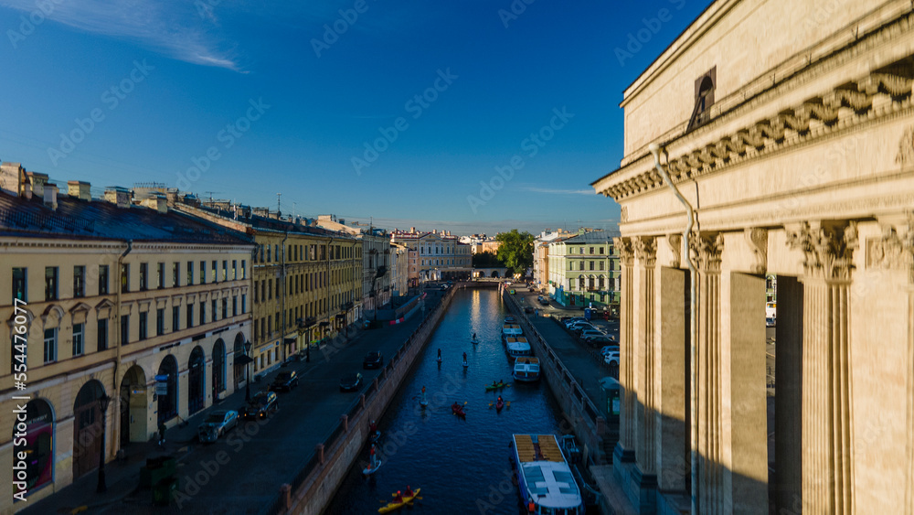Aerial view of the Kazan Cathedral in the historical and at the same time modern city of St. Petersburg at sunny summer dawn, drone flying back
