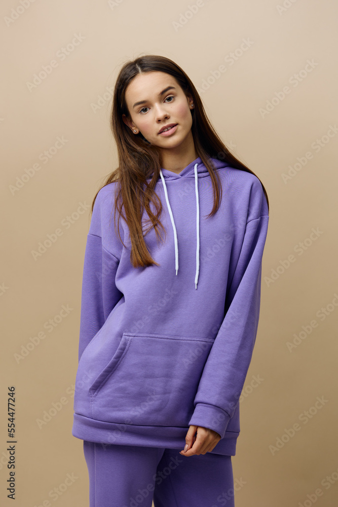 a beautiful, stylish, attractive woman stands on a beige background in a purple tracksuit and looks pleasantly, relaxed into the camera a beautiful, stylish, attractive woman stands on a beige background in a purple tracksuit and looks pleasantly, relaxed into the camera