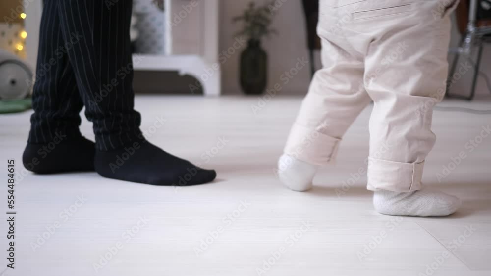 Toddler baby boy child legs trying to walk making first steps supported by granny Toddler baby boy child legs trying to walk making first steps supported by granny