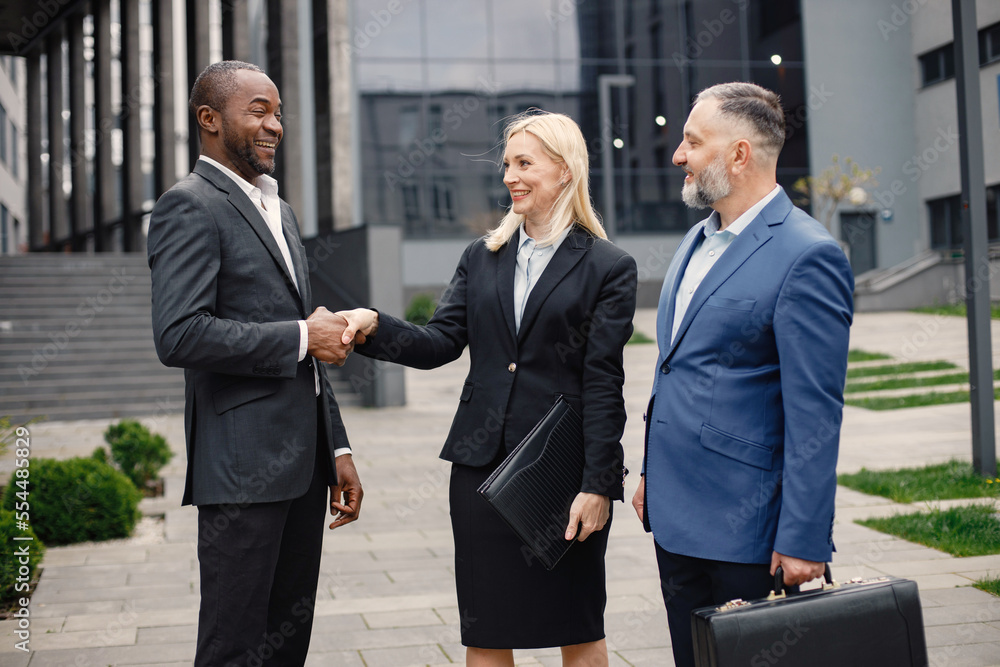 Business people standing and talk to each other in front of modern office Business people standing and talk to each other in front of modern office