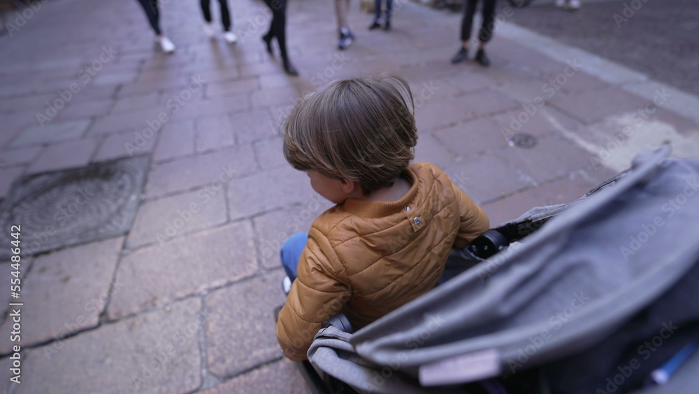 One child sitting in a stroller strolling in European street. 2 year old small boy seated. mother perspective One child sitting in a stroller strolling in European street. 2 year old small boy seated. mother perspective