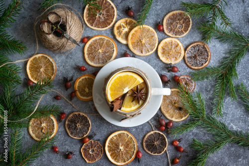A cup of hot tea with oranges and spices and dried oranges, which are used to make a New Year's garland, 2023 festive background.