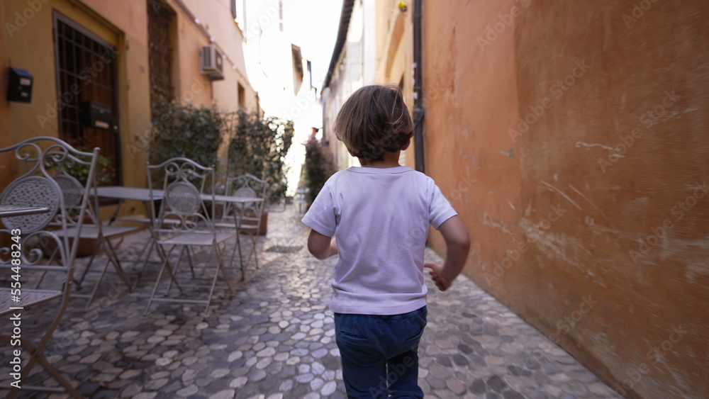 Back of child running in old european street. One little boy runs in Italian alley Back of child running in old european street. One little boy runs in Italian alley
