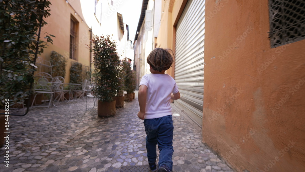 Back of child running in old european street. One little boy runs in Italian alley
