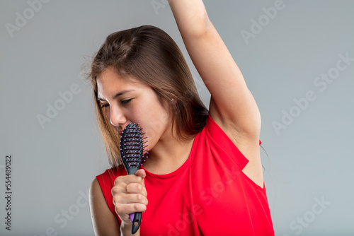 Young woman sings passionately with a hairbrush as a microphone