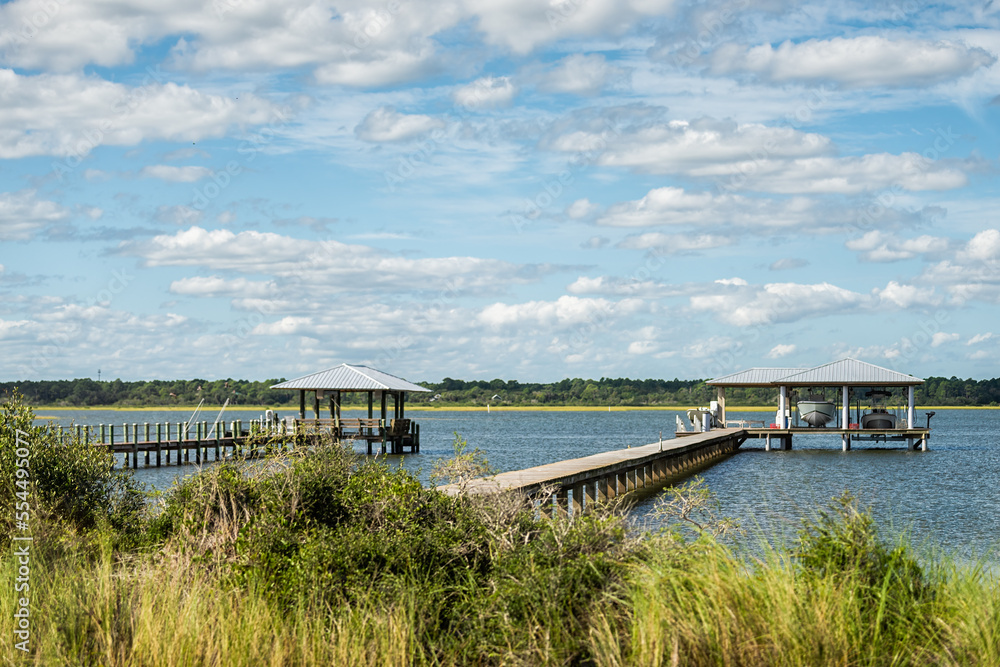 Island bay channel water of Matanzas River in Crescent Beach by Marineland, Florida with wooden docks pier and green grass marsh landscape view in north Florida coast Island bay channel water of Matanzas River in Crescent Beach by Marineland, Florida with wooden docks pier and green grass marsh landscape view in north Florida coast