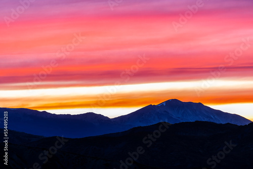Orange red pink cloudy sunset in Aspen, Colorado with Rocky mountains peak range, vibrant color of clouds at twilight with mountain ridge silhouette