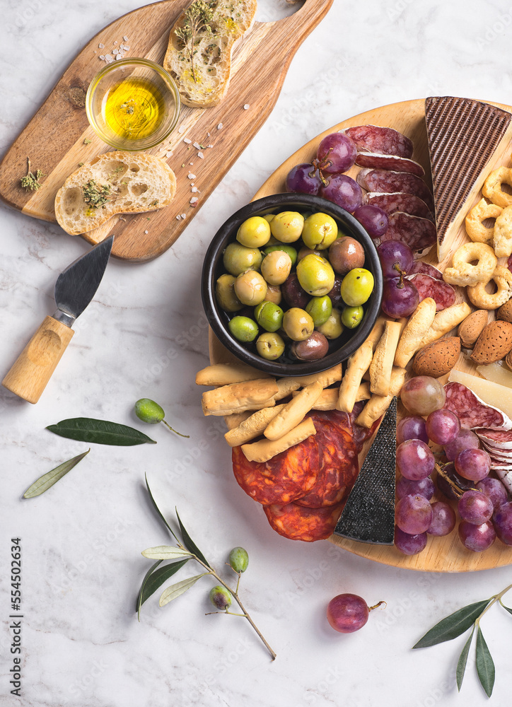 Appetizers boards with assorted  delicatessen cheese, salami, grape and nuts. Charcuterie and cheese platter, Spanish style and ingredients: olives, Pimientos, Chorizo, picos, cheese Semicurado - obrazy, fototapety, plakaty 