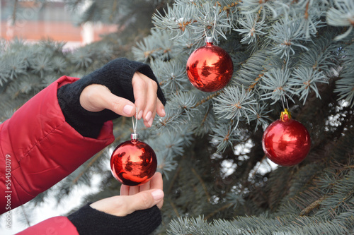 Fotografía The girl hangs a red ball on the Christmas tree