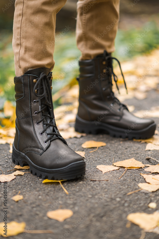 A military man in high black lace-up leather sneakers in a trench A military man in high black lace-up leather sneakers in a trench