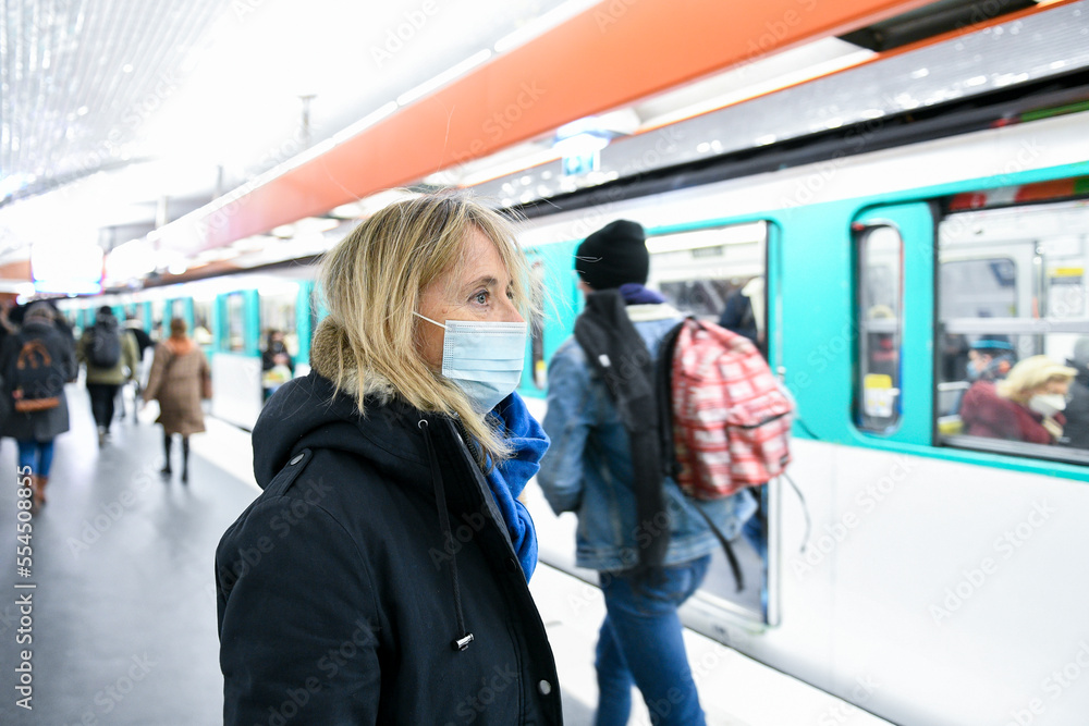 A person (woman) wearing a surgical blue mask on public transport due to the Covid-19 (coronavirus) pandemic in the parisian subway. A person (woman) wearing a surgical blue mask on public transport due to the Covid-19 (coronavirus) pandemic in the parisian subway.