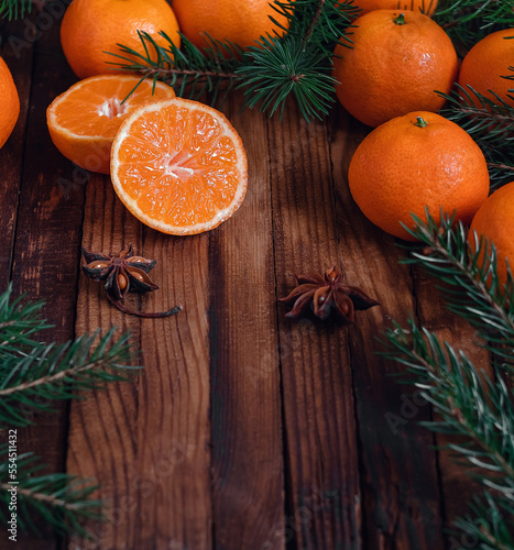 Fresh juicy tangerines and fir tree branches on a dark wooden table. Merry Christmas and happy New Year concept.