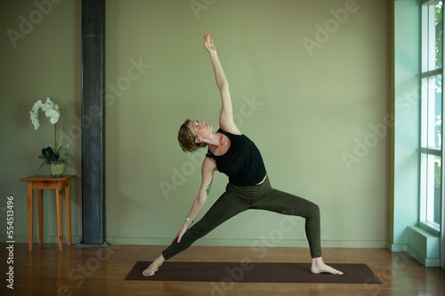 Woman practicing yoga inside of a window lit yoga studio, 