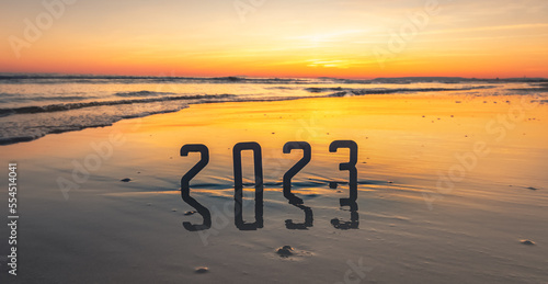 Bonne année 2023 : concept de nouvelle année 2023 avec un lever de soleil sur la plage et les chiffres 2023 en reflet dans la mer.