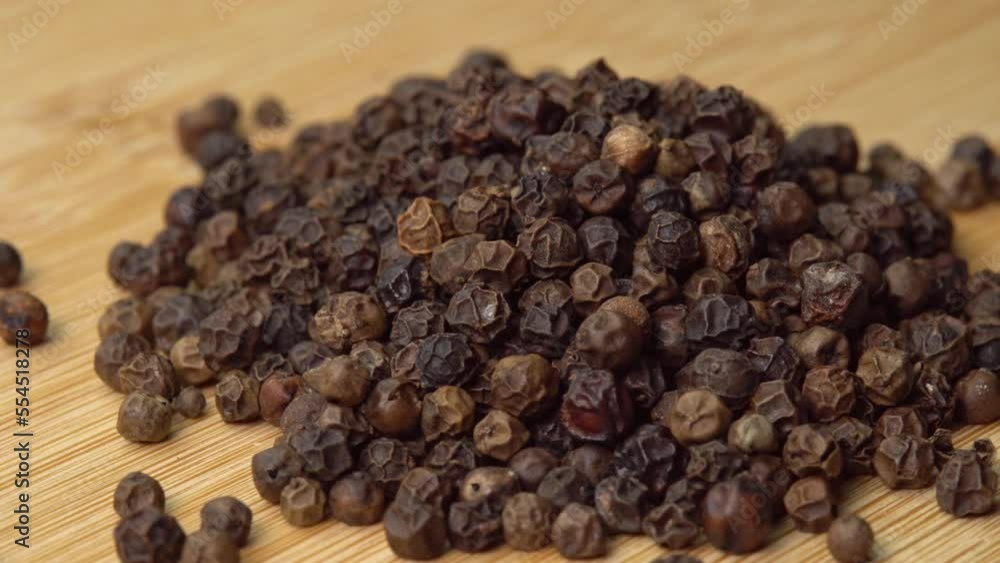 Peppercorns or black pepper spice lies on wooden board rotating. Dry seasoning on wooden board. Spices and herbs for cooking Peppercorns or black pepper spice lies on wooden board rotating. Dry seasoning on wooden board. Spices and herbs for cooking