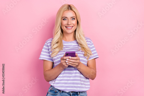 Photo of pretty positive lady used modern device iphone samsung writing friends free time good mood isolated on pink color background