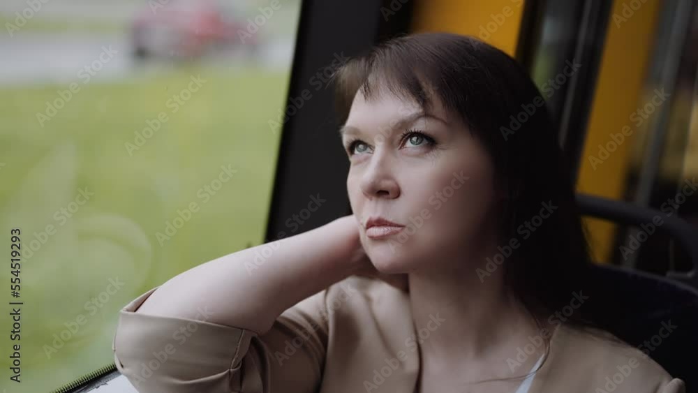a woman travels looking out the window while sitting in a train or bus. a woman travels looking out the window while sitting in a train or bus.