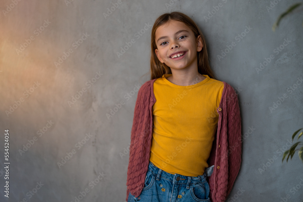 Beautiful young girl wearing mustard yellow blouse and a cardigan looking at camera and smiling. Human emotions and facial expressions concept. Beautiful young girl wearing mustard yellow blouse and a cardigan looking at camera and smiling. Human emotions and facial expressions concept.