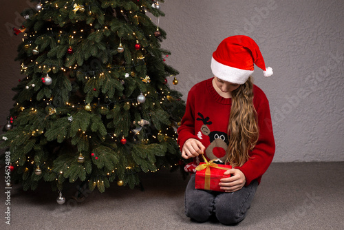 European girl holding a gift near the Christmas tree. Christmas gifts on the background