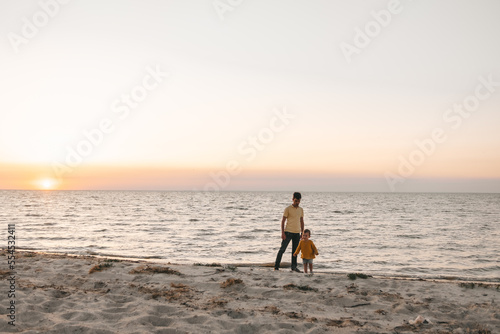 Dad and child on the sandy beach at sunset