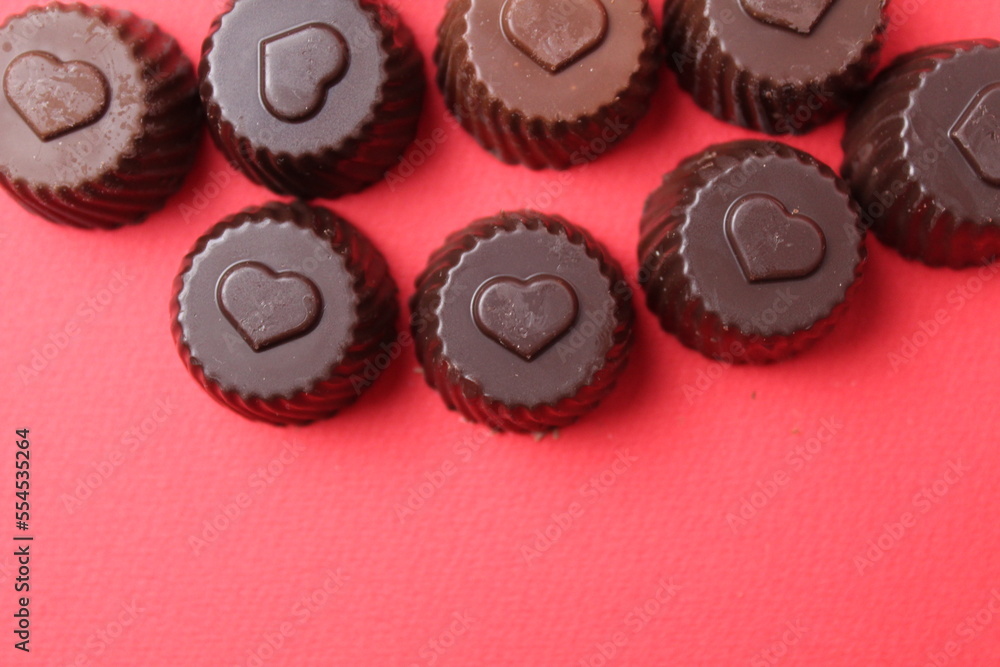 chocolate case candies with the symbol of the heart. Valentine's Day of Chocolate Sweets. Candy bonbon on a red background with space for copyspace text chocolate case candies with the symbol of the heart. Valentine's Day of Chocolate Sweets. Candy bonbon on a red background with space for copyspace text
