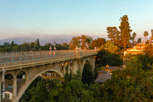 aerial shot of the Colorado Street Bridge surrounded by homes, lush green trees, grass and plants, majestic mountains at sunset in Pasadena California USA photo