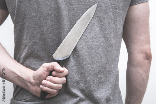 Man holding a kitchen knife behind his back.