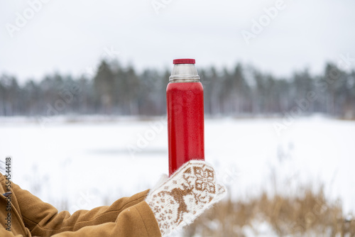 Wallpaper Mural A girl in woolen mittens holds a red thermos with tea in her hands in a winter forest Torontodigital.ca