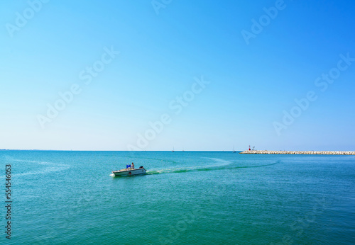 Adriatic sea, waves, boat with people and landscape. Rimini, Italy. © Trambitski