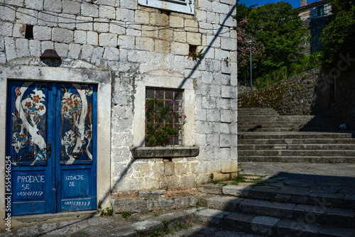Facade of an old house. Mediterranean building. Steps up. Blue door. Textured stonework.