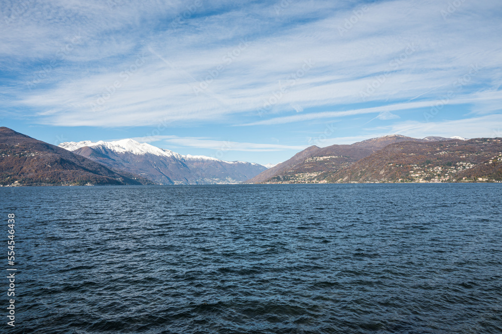 Lake Maggiore with snow capped mountains, blue sky and white clouds