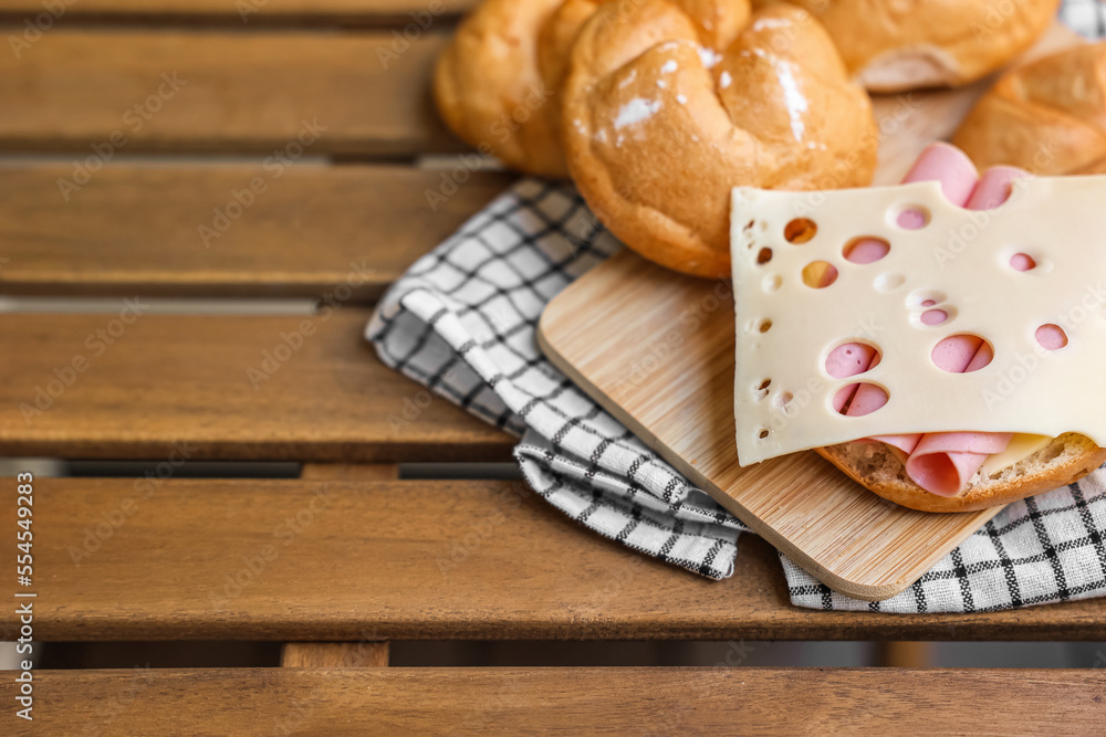 Delicious kaiser rolls with ham and cheese on wooden board Delicious kaiser rolls with ham and cheese on wooden board
