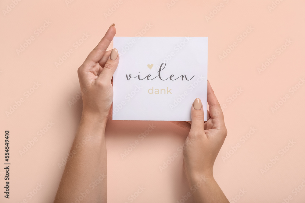 Φωτογραφία Woman holding card with text VIELEN DANK on color background, closeup
