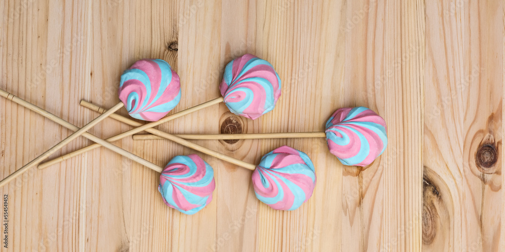 Colorful fluffy marshmallows on sticks on a background of a light wooden surface Colorful fluffy marshmallows on sticks on a background of a light wooden surface