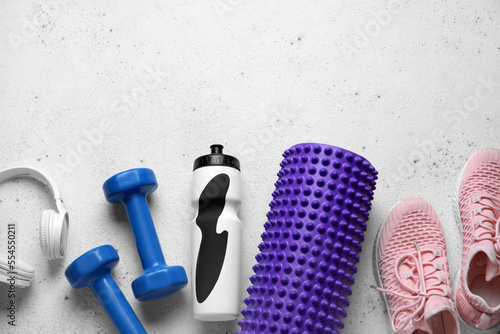Different sports equipment, bottle of water and headphones on light background