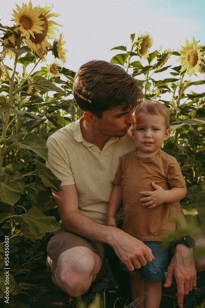 Obraz premium portrait of a father and child in a field with sunflowers in summer