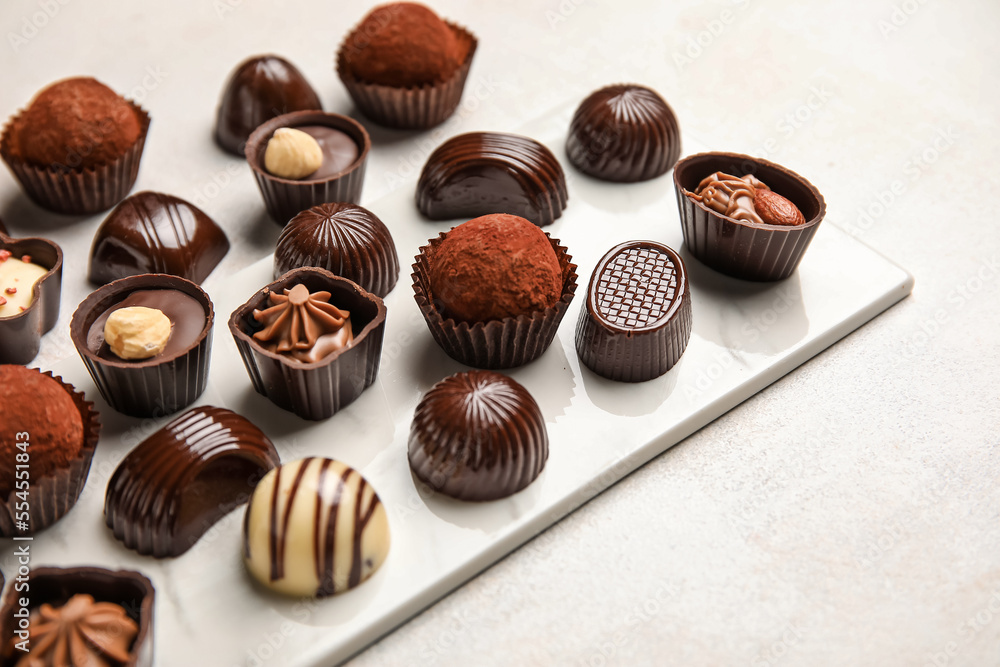 Board with chocolate candies on white background, closeup Board with chocolate candies on white background, closeup