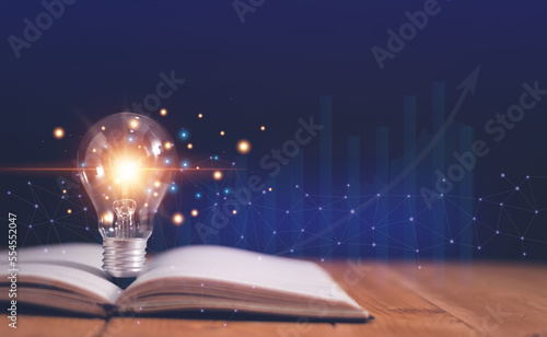 Light bulb on open book with growing graphs of stock market, Educational knowledge and business education concepts, Reading for inspiration and new idea to business grow in the future.