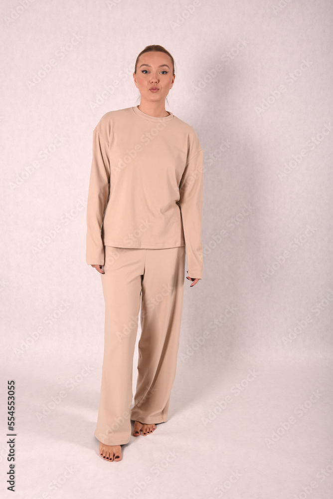 © Шамиль Алиев - A young girl in beige home clothes on a white background in the studio
