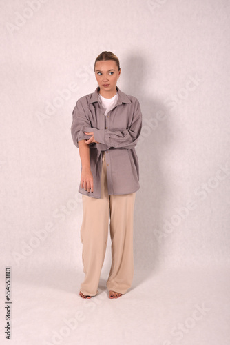 A young girl in beige home clothes on a white background in the studio
