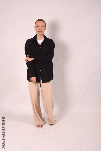 A young girl in beige home clothes and a black shirt on a white background in the studio