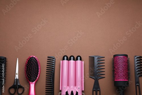 Flat lay composition of professional hairdresser tools on brown background, space for text