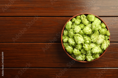 Bowl with fresh green hops on wooden table, top view. Space for text