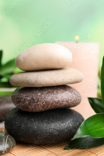 Stacked spa stones and bamboo leaves on mat  closeup