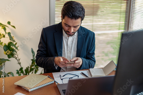 Handsome indian businessman use phone while working from home office . High quality photo © Yaroslav Astakhov