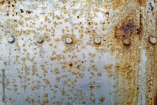 Detail of a rusty metal surface with a line of bolts