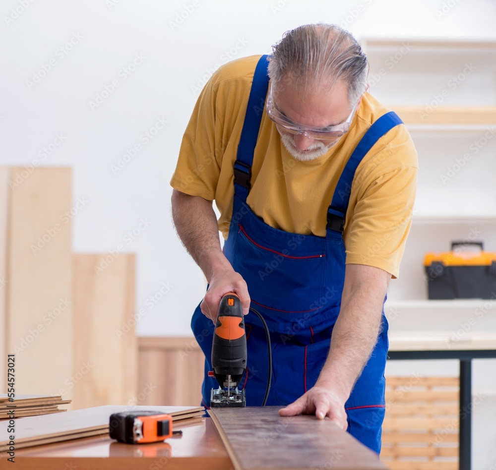 Old male carpenter working in workshop Old male carpenter working in workshop